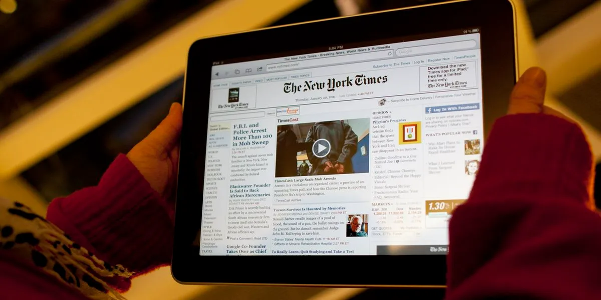 Hands holding a tablet displaying a busy news homepage with banner advertisements